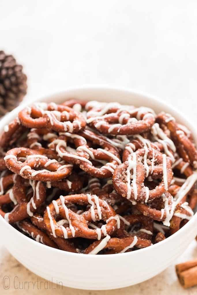 white chocolate drizzled cinnamon pretzels in a white bowl.