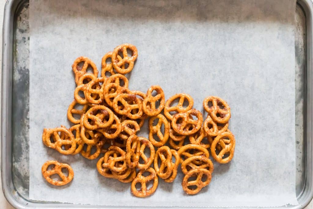 arranging cinnamon-coated pretzels on a baking tray.