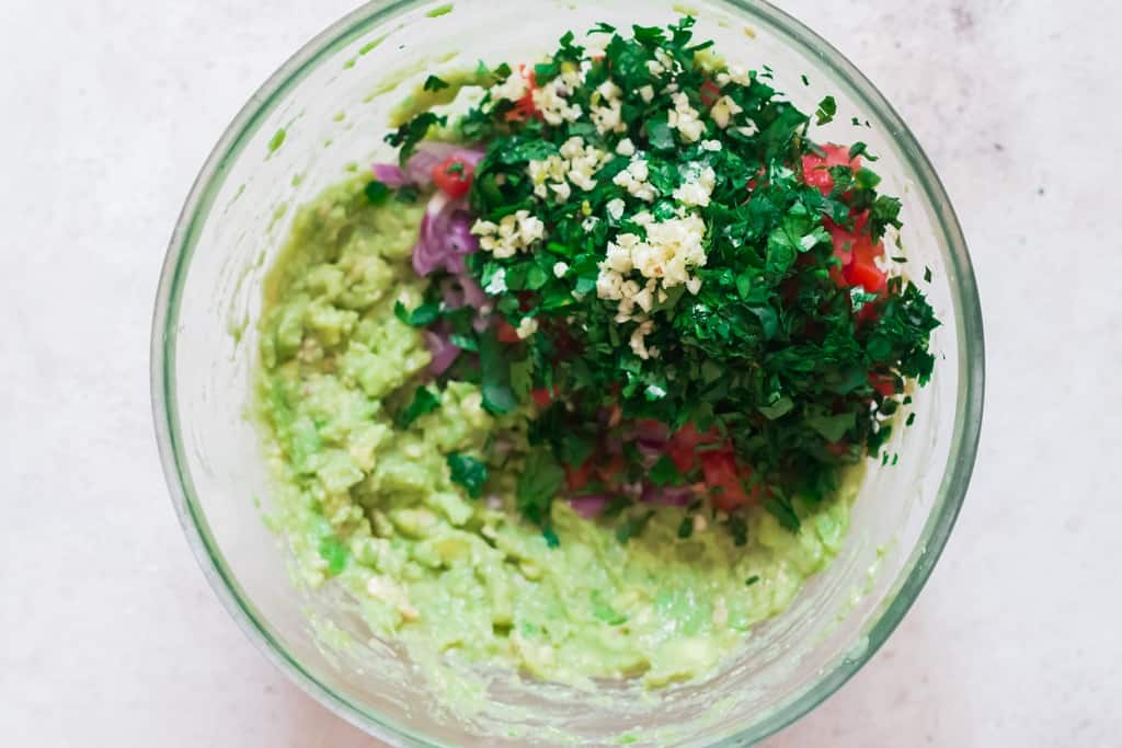 mixing all guacamole ingredients in bowl with fork