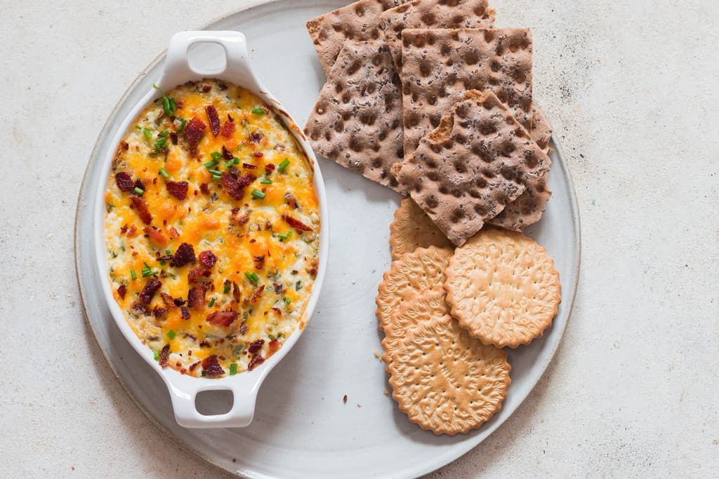 hot and bubbly cream cheese dip in a casserole dish garnished with bacon and scallions.