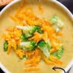 Broccoli and cheddar soup served in white bowl with text overlay