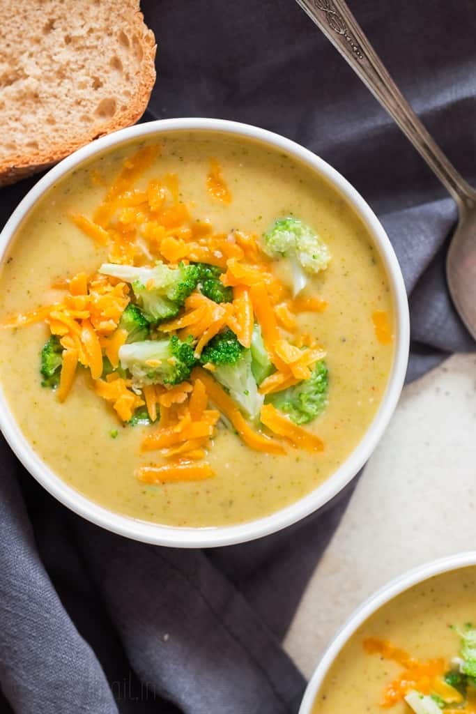 panera copycat broccoli cheddar soup in white bowl crusty bread on side