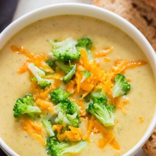 panera copycat broccoli cheddar soup in white bowl crusty bread on side