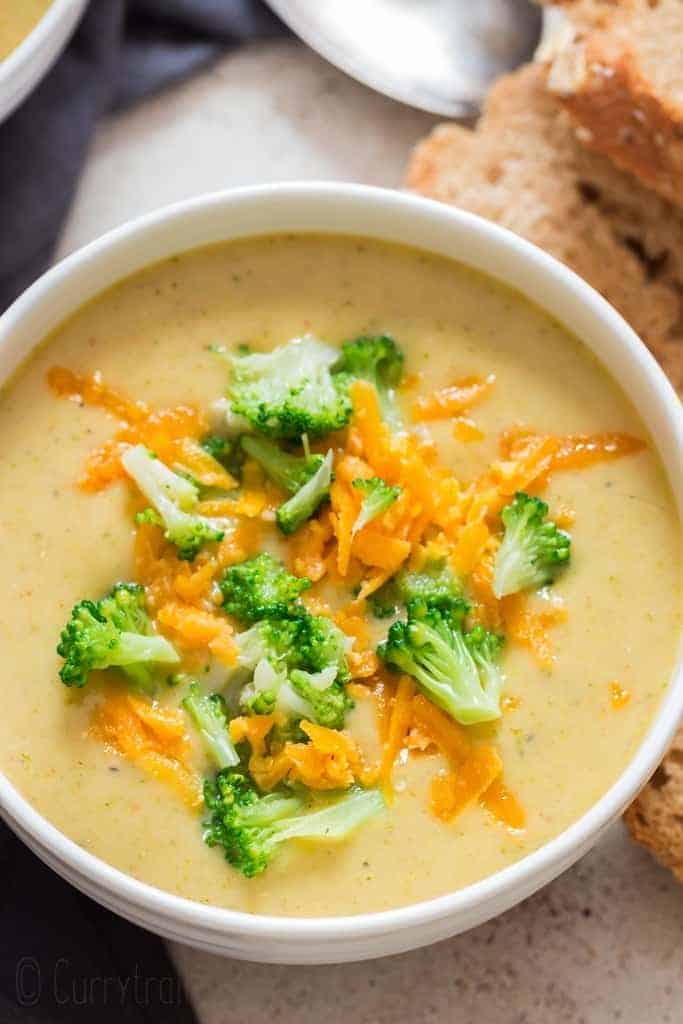 panera copycat broccoli cheddar soup in white bowl crusty bread on side