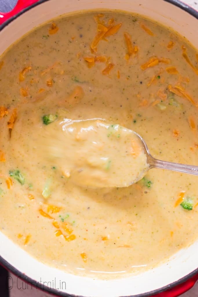 spooning broccoli cheddar soup from soup pot
