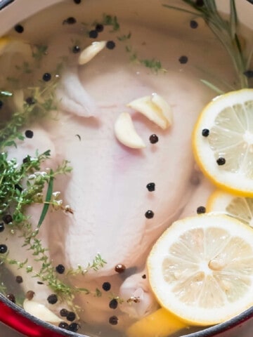 whole chicken in large pot with aromatics