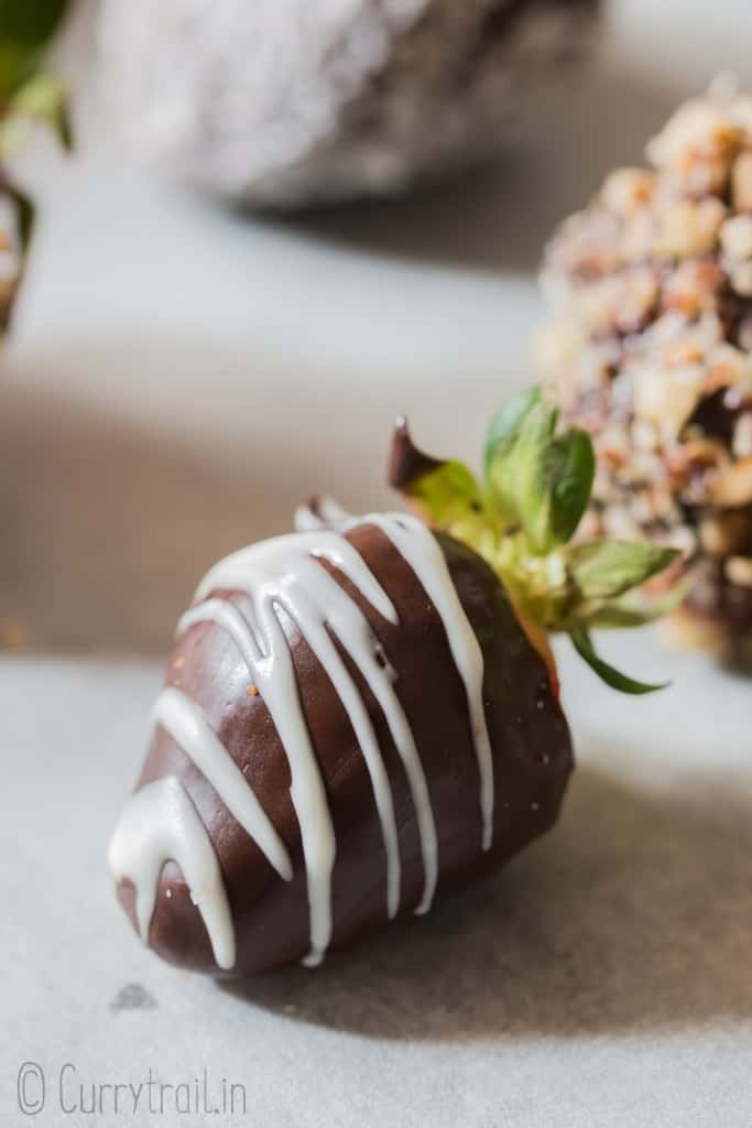 Chocolate-covered strawberries decorated with chopped nuts, desiccated coconut, and chocolate drizzle.