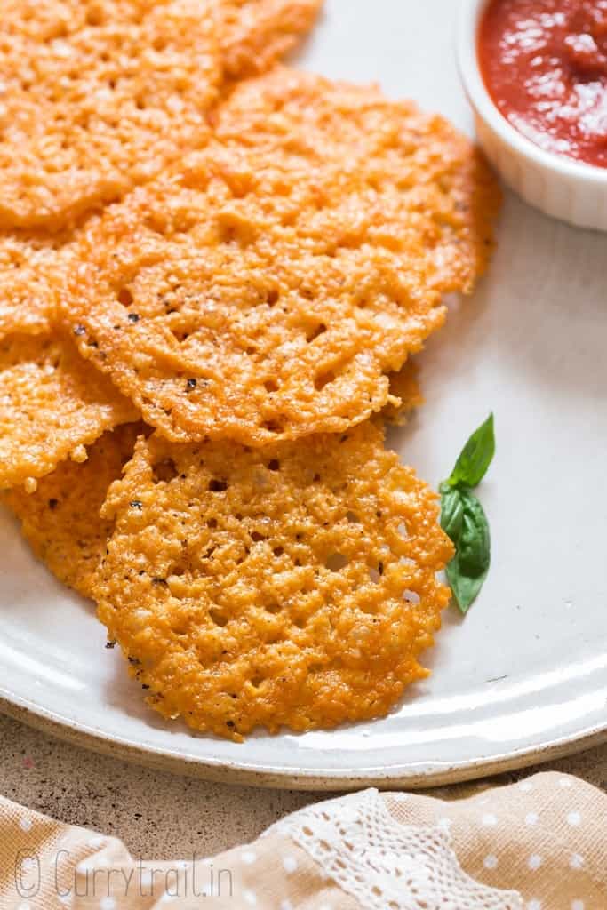 baked parmesan crisps served on white plate with sauce