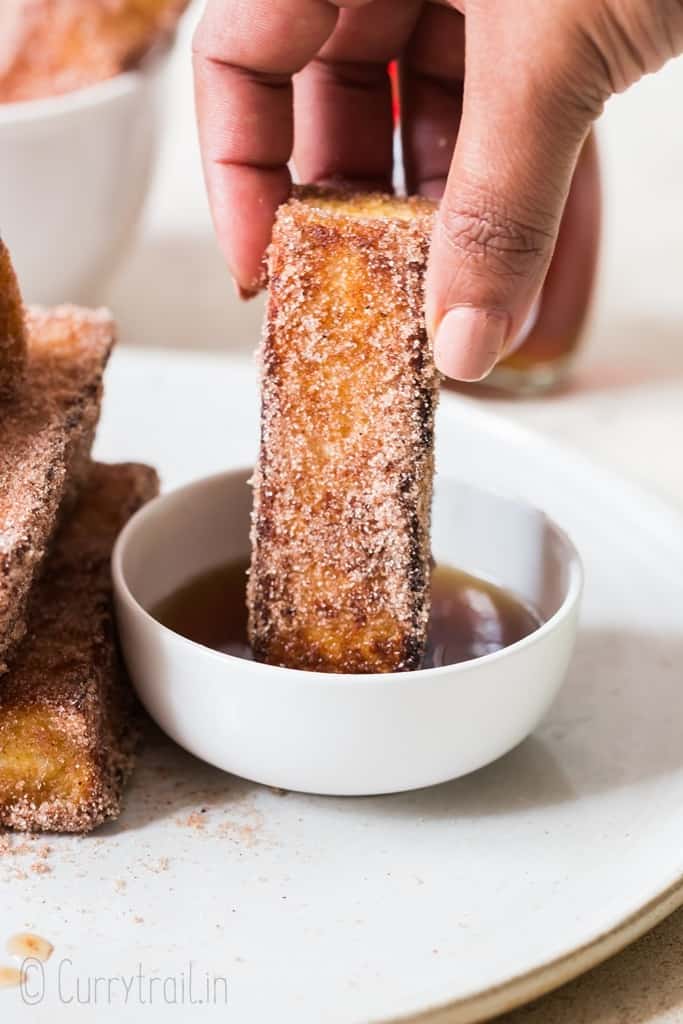 dipping cinnamon French toast sticks in pure maple syrup