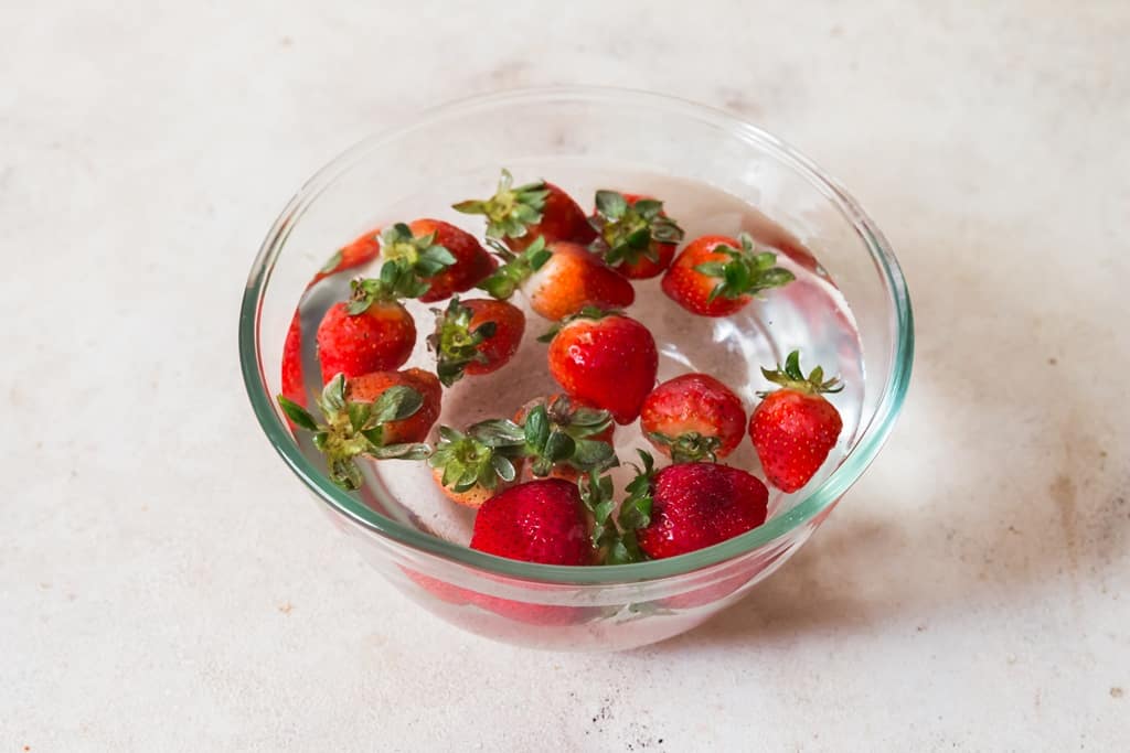 rinse strawberries in water in a bowl.