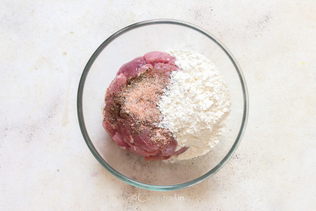 lamb pieces coated in flour, salt, and pepper in a bowl.