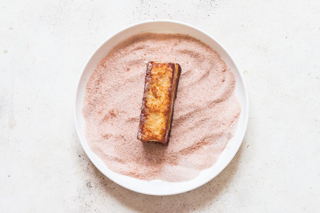 coating hot bread sticks in cinnamon sugar