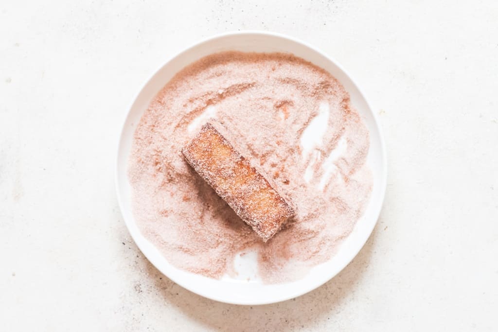 coating hot bread sticks in cinnamon sugar