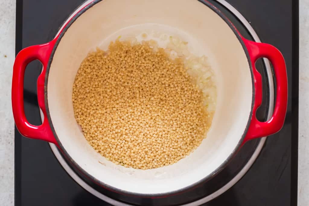pearl couscous was added to the cooking pot along with onion and garlic.