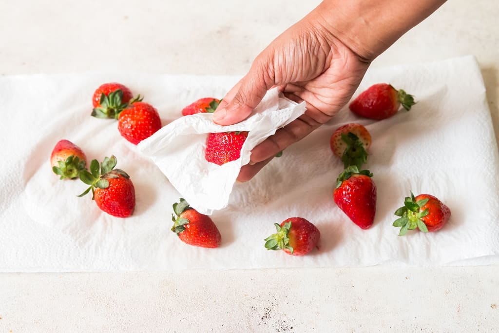 pat drying strawberries in paper towel.