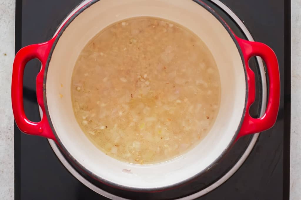 cooking pearl couscous in a pot with onion and garlic.