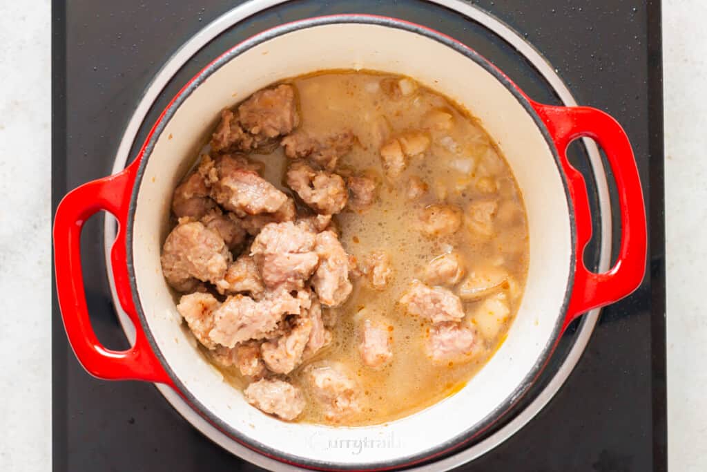 browned meat and stock are added to the pot.