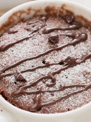 close up view of microwave chocolate mug cake in a white mug with chocolate chips.