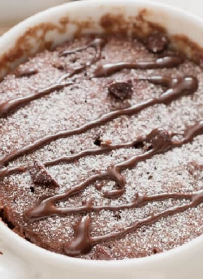 close up view of microwave chocolate mug cake in a white mug with chocolate chips.