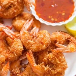 crispy coconut shrimp with sweet chili sauce for dipping on white plate