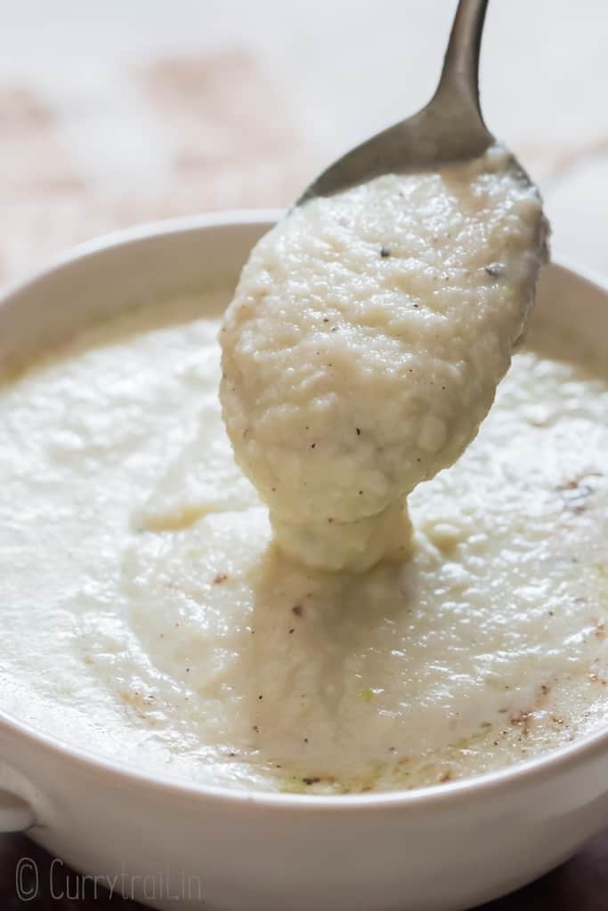 pouring cauliflower cheese sauce served in white bowl