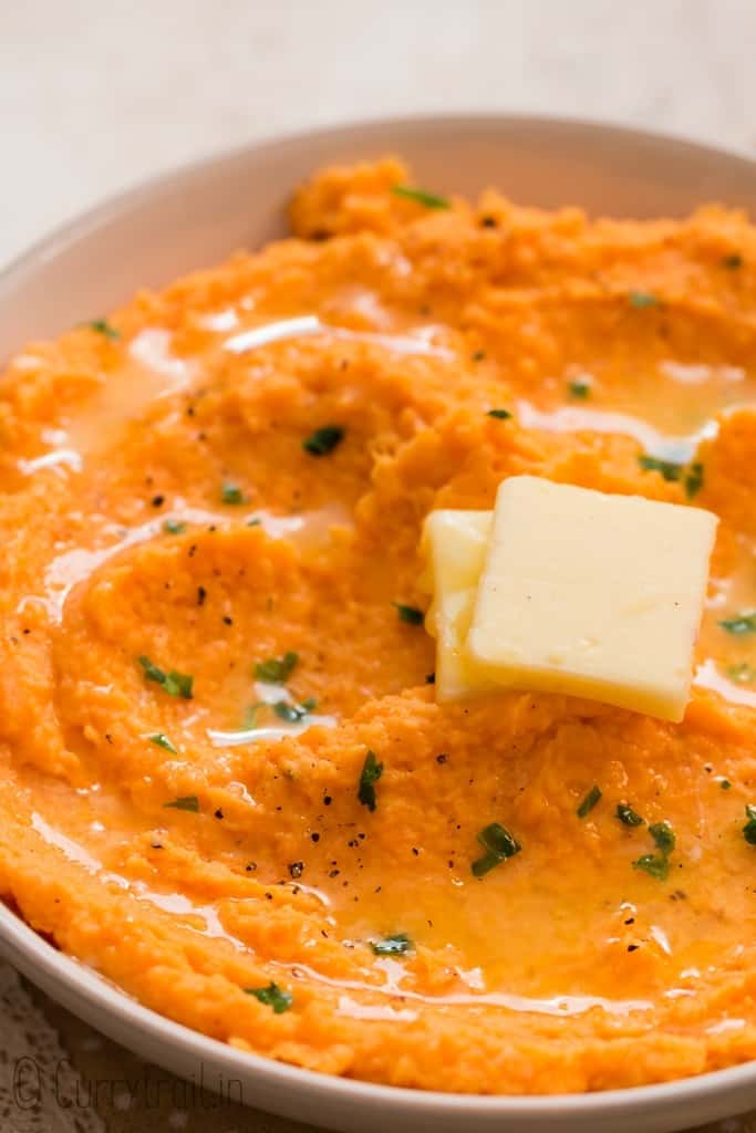 savory mashed sweet potatoes served iwth cubed butter in white bowl