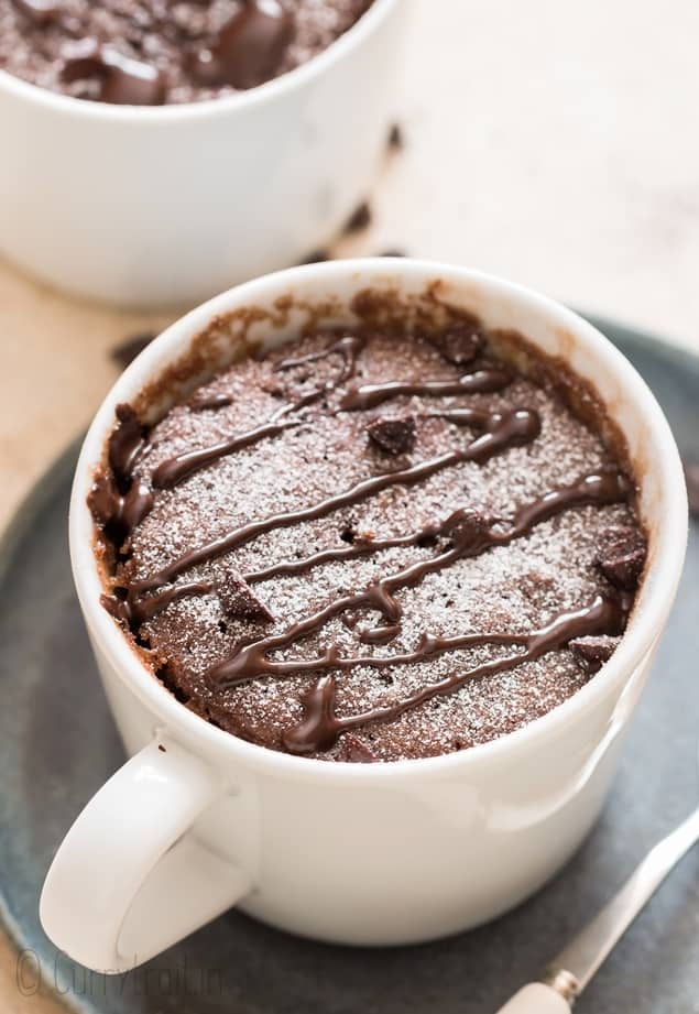 microwave chocolate mug cake in a white mug with chocolate chips.