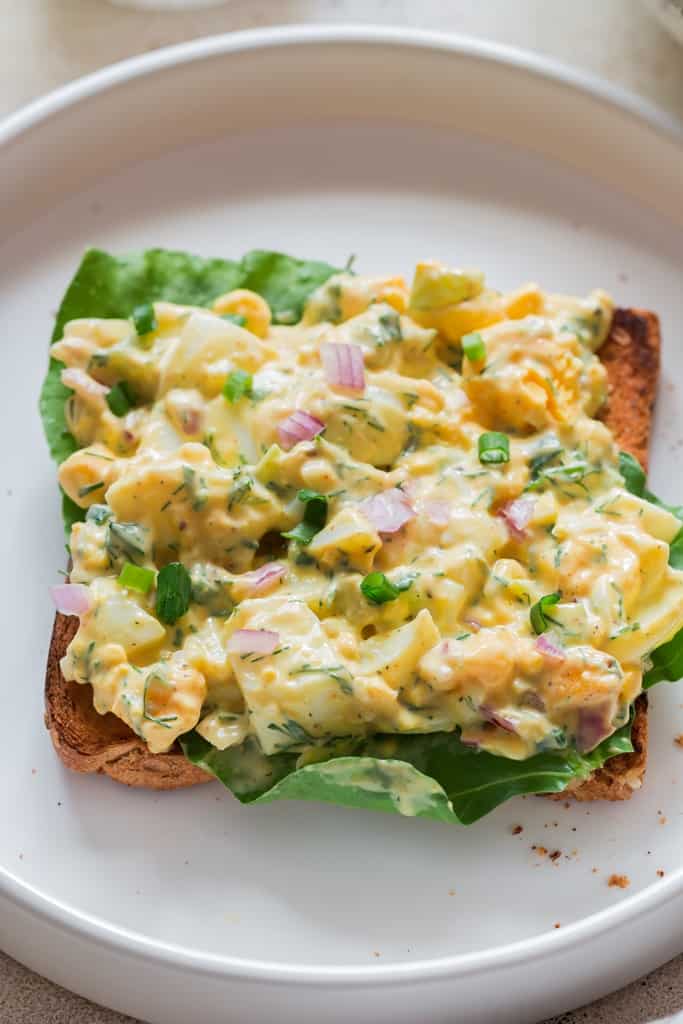salad made of eggs spread over sandwich server with salad greens