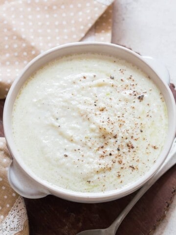 cheesy cauliflower cheese sauce served in while bowl with napkin on side