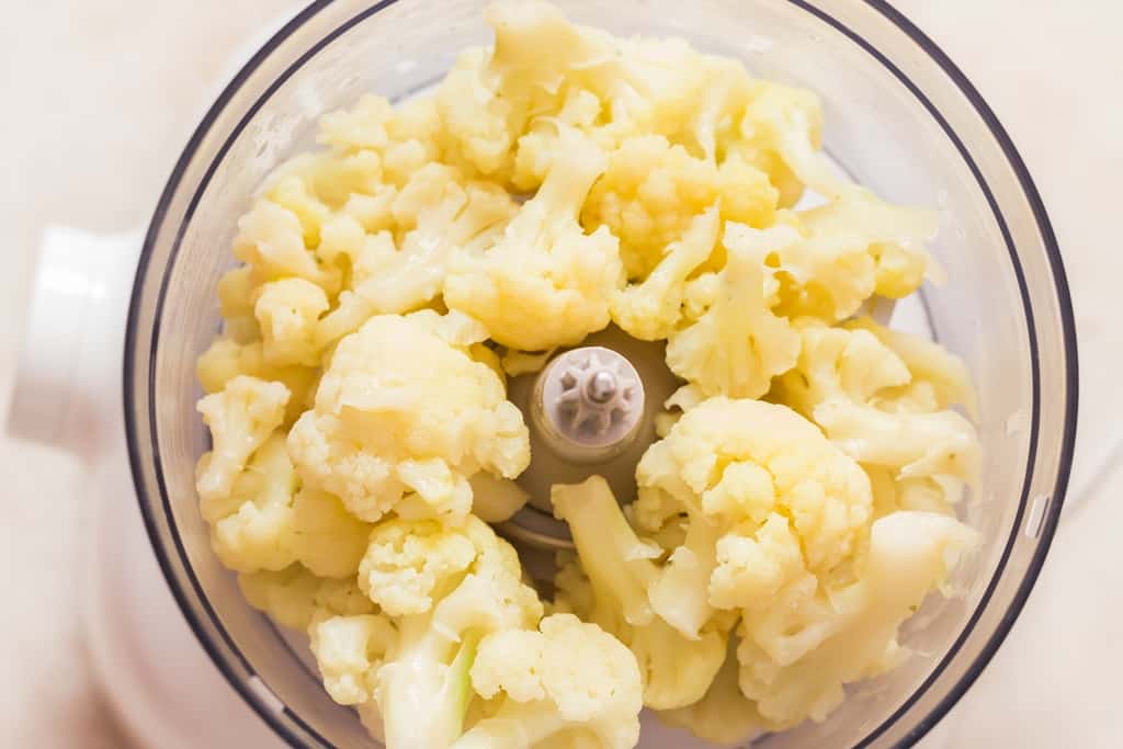 tender cauliflower florets added into food processor for blending