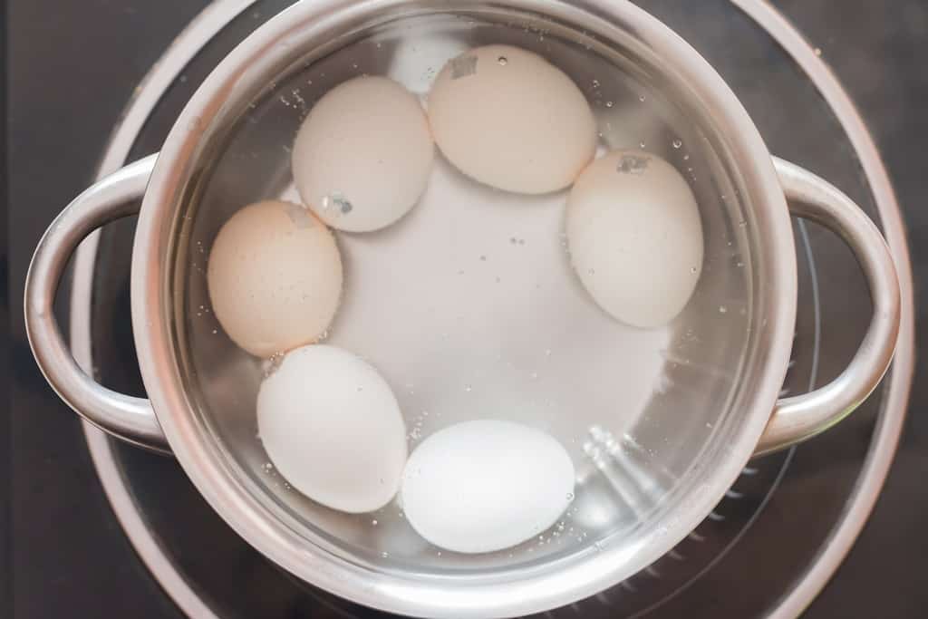 boiling eggs in a pan to make egg salad.