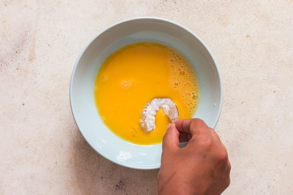 coating shrimps in beaten eggs.