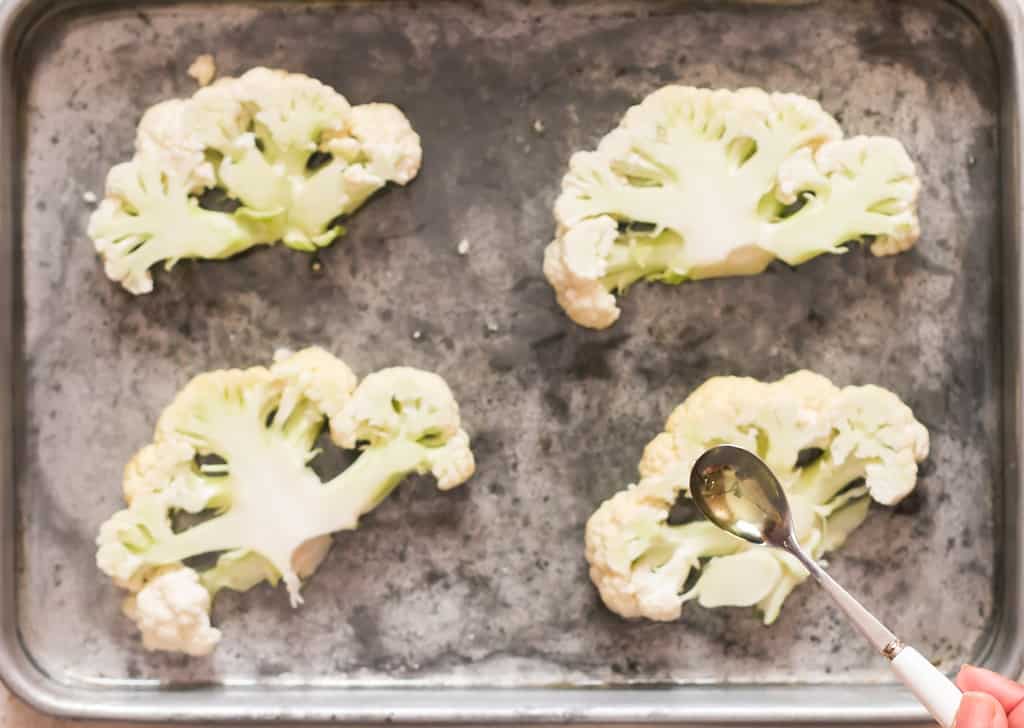 drizzling olive oil over cauliflower steaks 