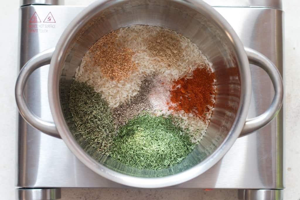 rice, spices, and dried herbs in a cooking pot.