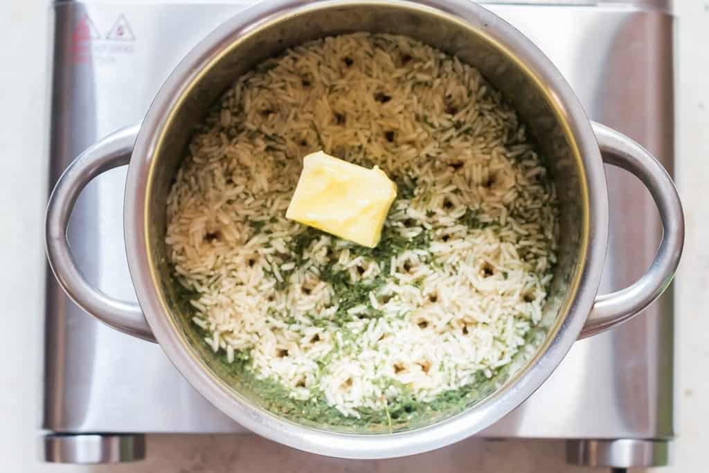 butter is added to seasoned rice in the cooking pot.