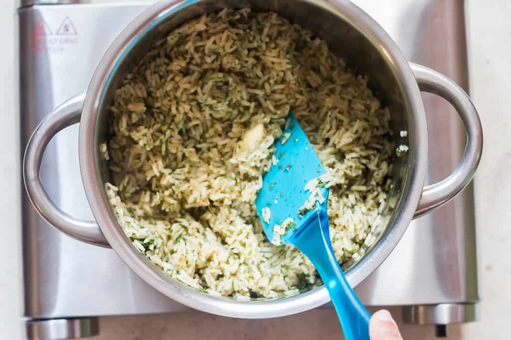 fluffing seasoned rice with a silicon spatula in the pot.