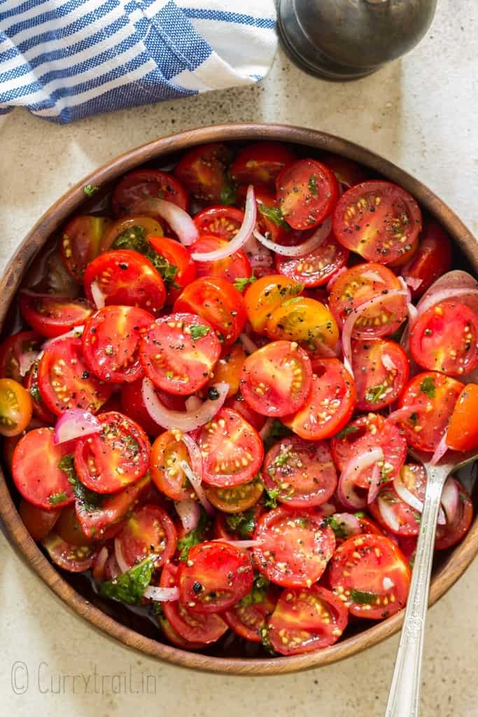 summer cherry tomato salad served in wooden salad bowl with pepper mill on side