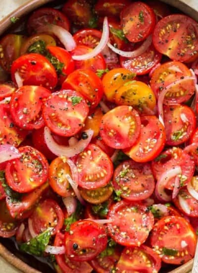 cherry tomato salad in a wooden salad bowl with a spoon in it.