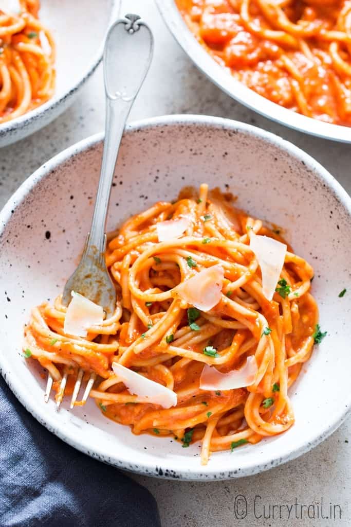 roasted red bell pepper pasta served in white bowl with Parmesan shavings