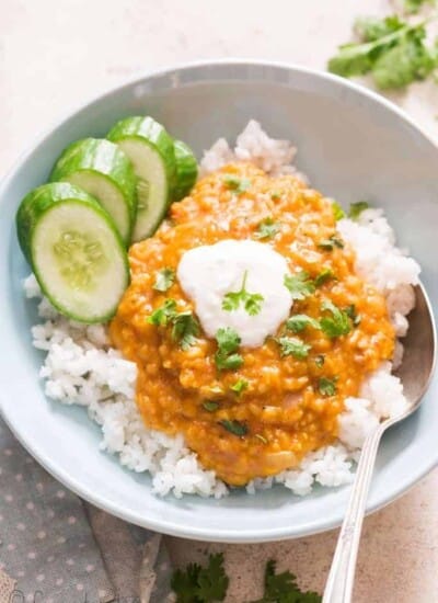 red lentil curry served over bowl of rice and garnish with cilantro