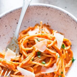 roasted red bell pepper pasta served in white bowl with Parmesan shavings