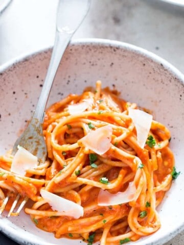 roasted red bell pepper pasta served in white bowl with Parmesan shavings