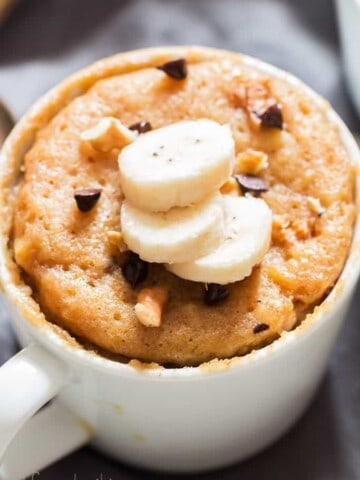 1 minute microwave banana mug cake in white ceramic mug served with banana slices