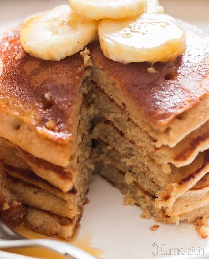 easy banana oatmeal pancake served with banana slices and maple syrup on ceramic plate