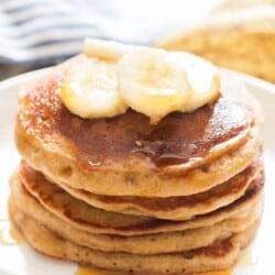 easy banana oatmeal pancake served with banana slices and maple syrup on ceramic plate