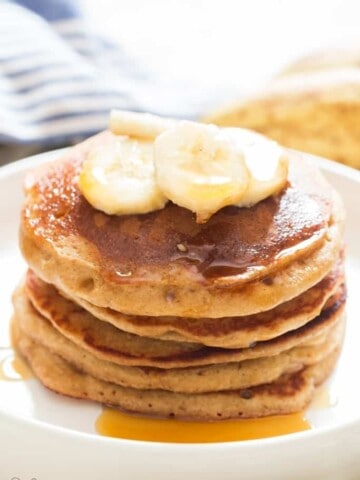 easy banana oatmeal pancake served with banana slices and maple syrup on ceramic plate