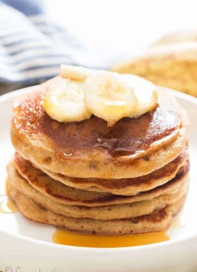 easy banana oatmeal pancake served with banana slices and maple syrup on ceramic plate