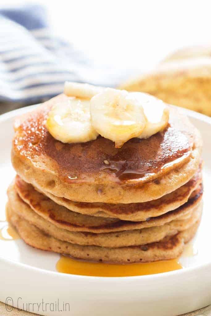 easy banana oatmeal pancake served with banana slices and maple syrup on ceramic plate