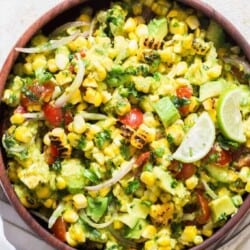 corn salad with avocados and cherry tomatoes in wooden bowl