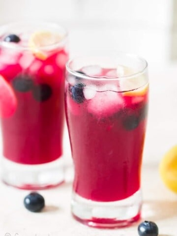 blueberry lemonade with lemon wedges served in two glasses